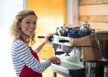 Młoda kobieta czyści ekspres do kawy