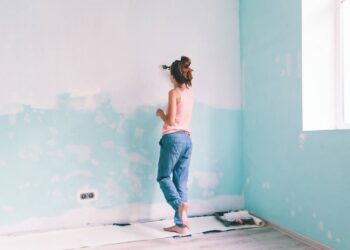 Kobieta maluje pędzlem ścianę w pokoju